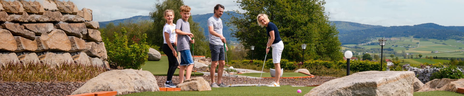 Eine Familie beim Minigolf spielen im Golfpark.